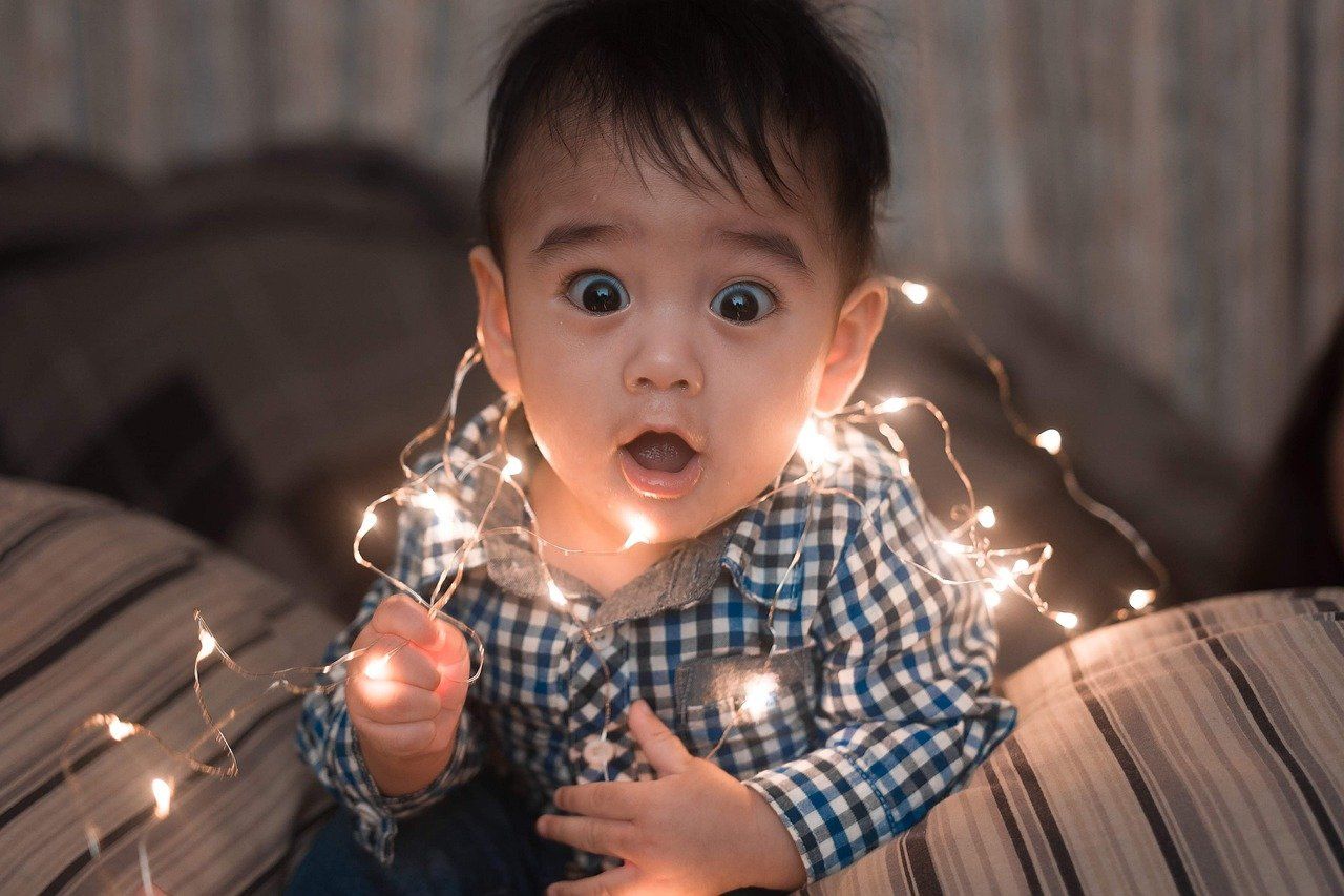 child with shocked look with string lights