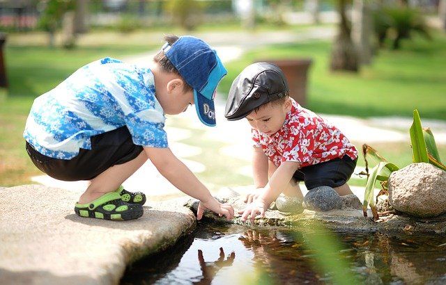 two children outside with hands in water